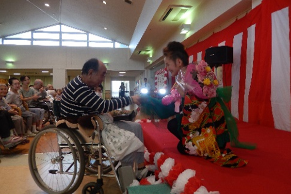 介護施設内での夏祭りイベント。浴衣姿の入居者と職員が和やかに交流している